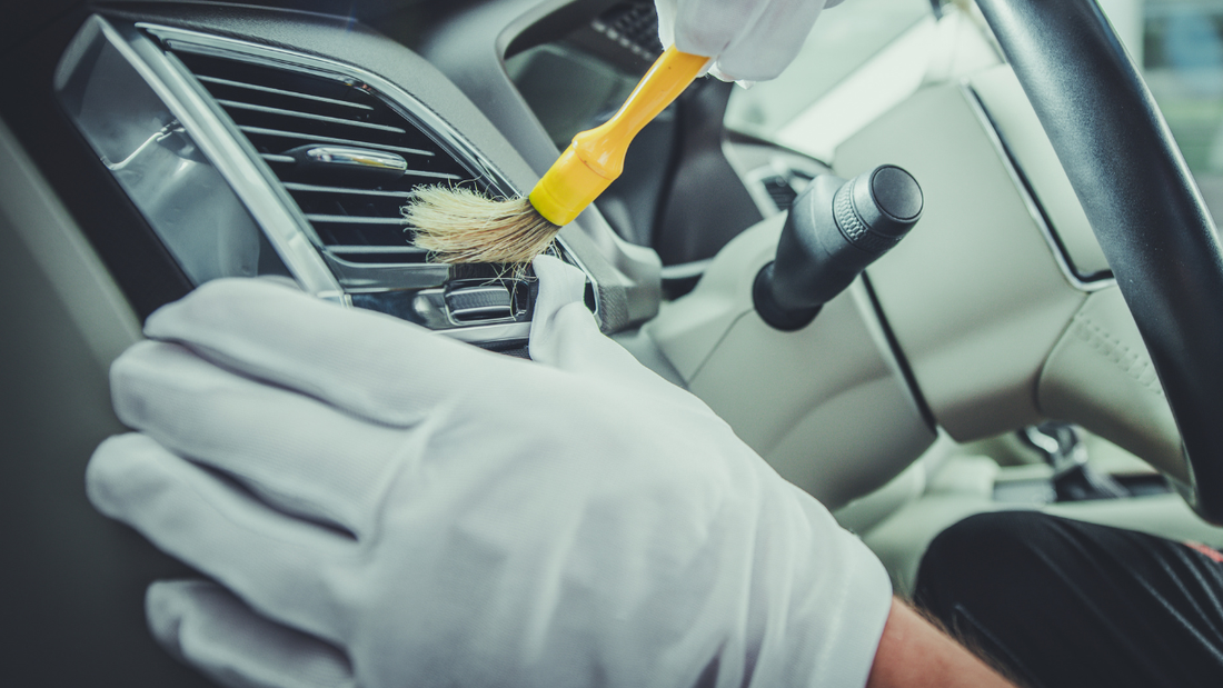 cleaning car air vents with brush during interior detailing to maintain a clean car interior